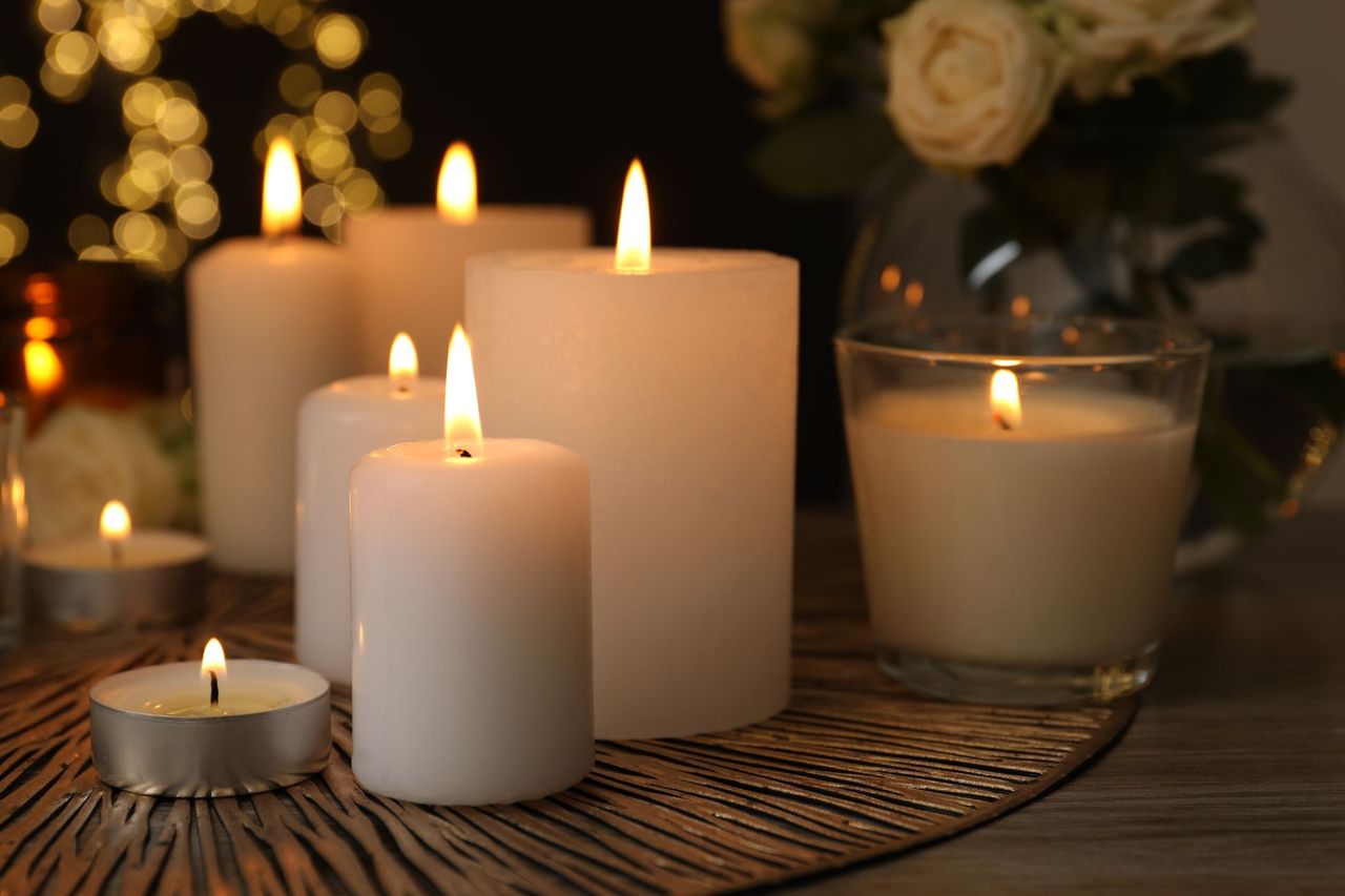Lit candles and tea lights on a woven tray, creating a warm, cozy glow.