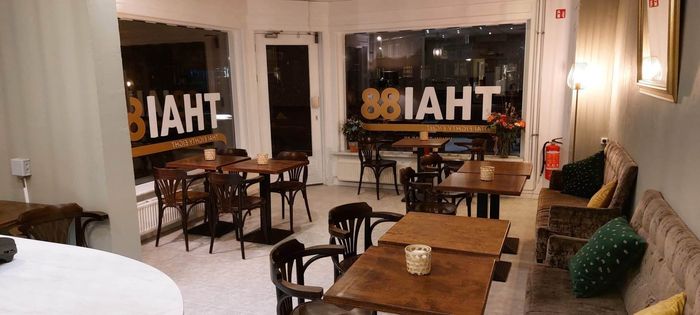 Interieurfoto van een gezellig café met houten tafels, stoelen en zitjes in nisjes, met 