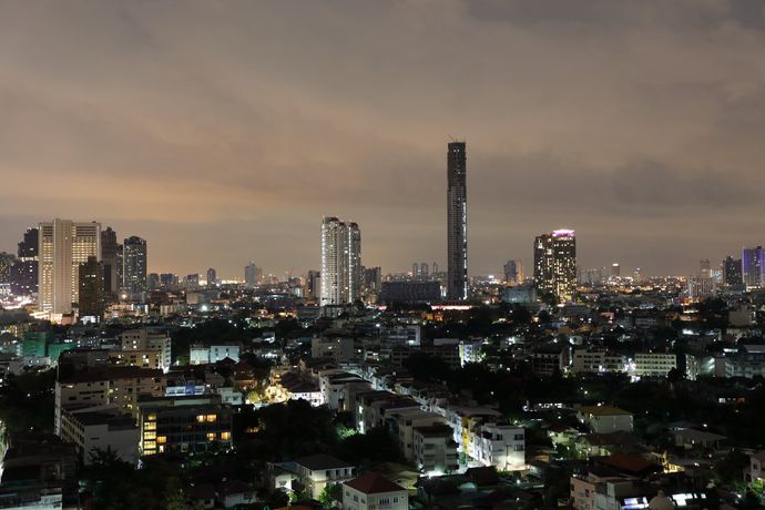 De skyline van een stad 's nachts, met verlichte wolkenkrabbers en woongebouwen tegen een wazige, schemerige hemel.
