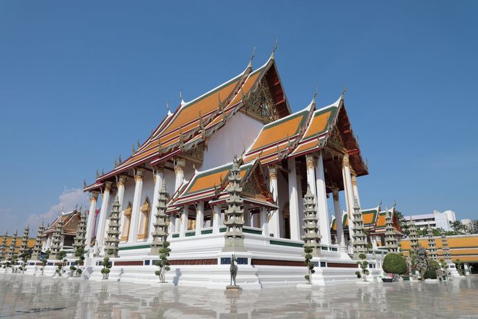 Wat Benchamabophit, een Thaise tempel met witte marmeren muren, oranje daken in verschillende lagen en pilaren onder een helderblauwe hemel.