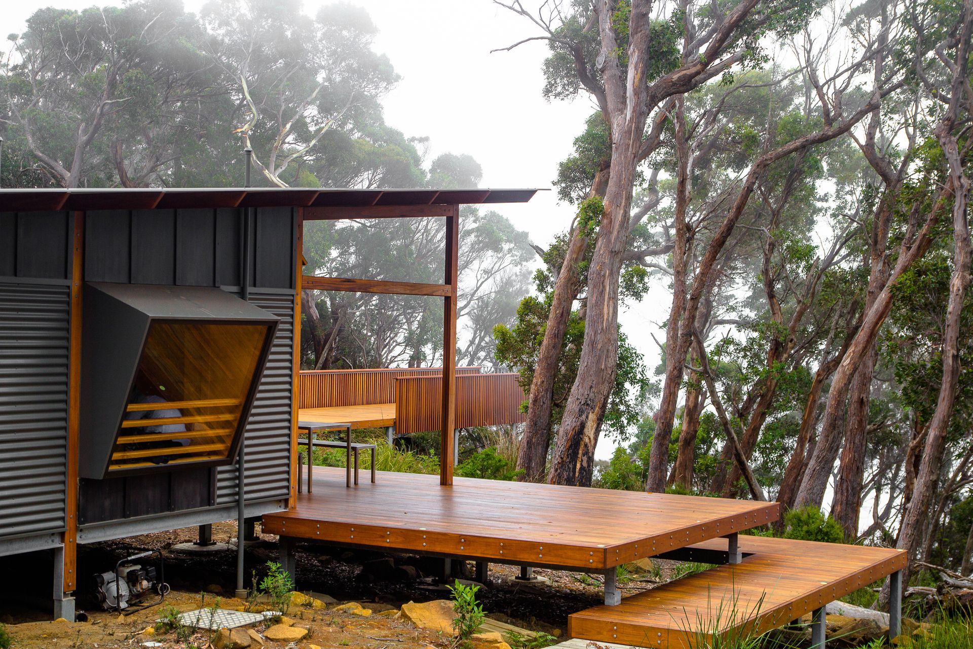 A small house with a wooden deck in the middle of a forest