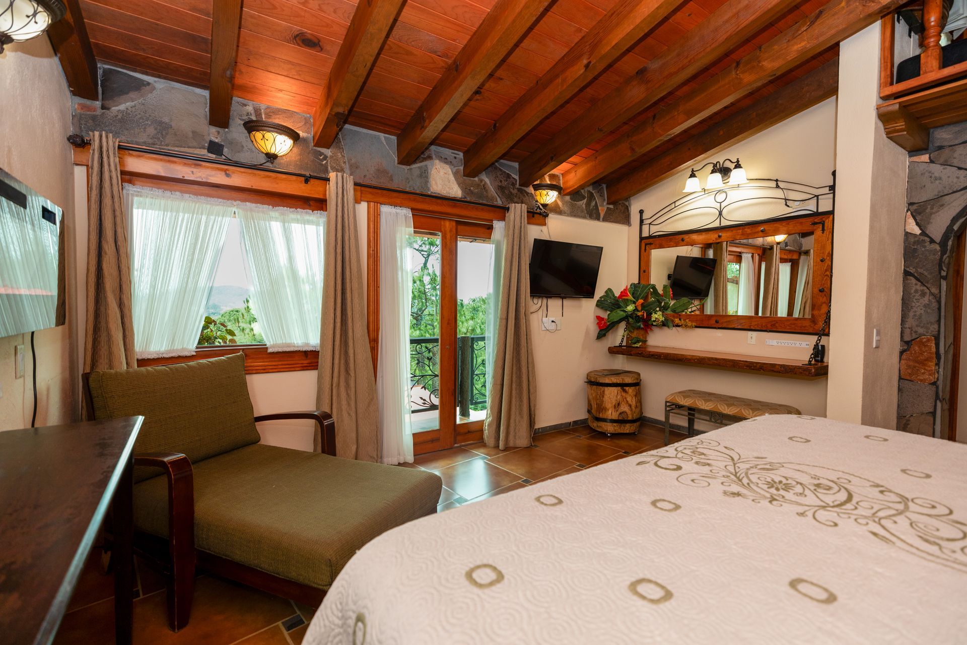 Acogedora habitación con techo de madera, cama, sofá, puertas correderas y espejo de tocador.
