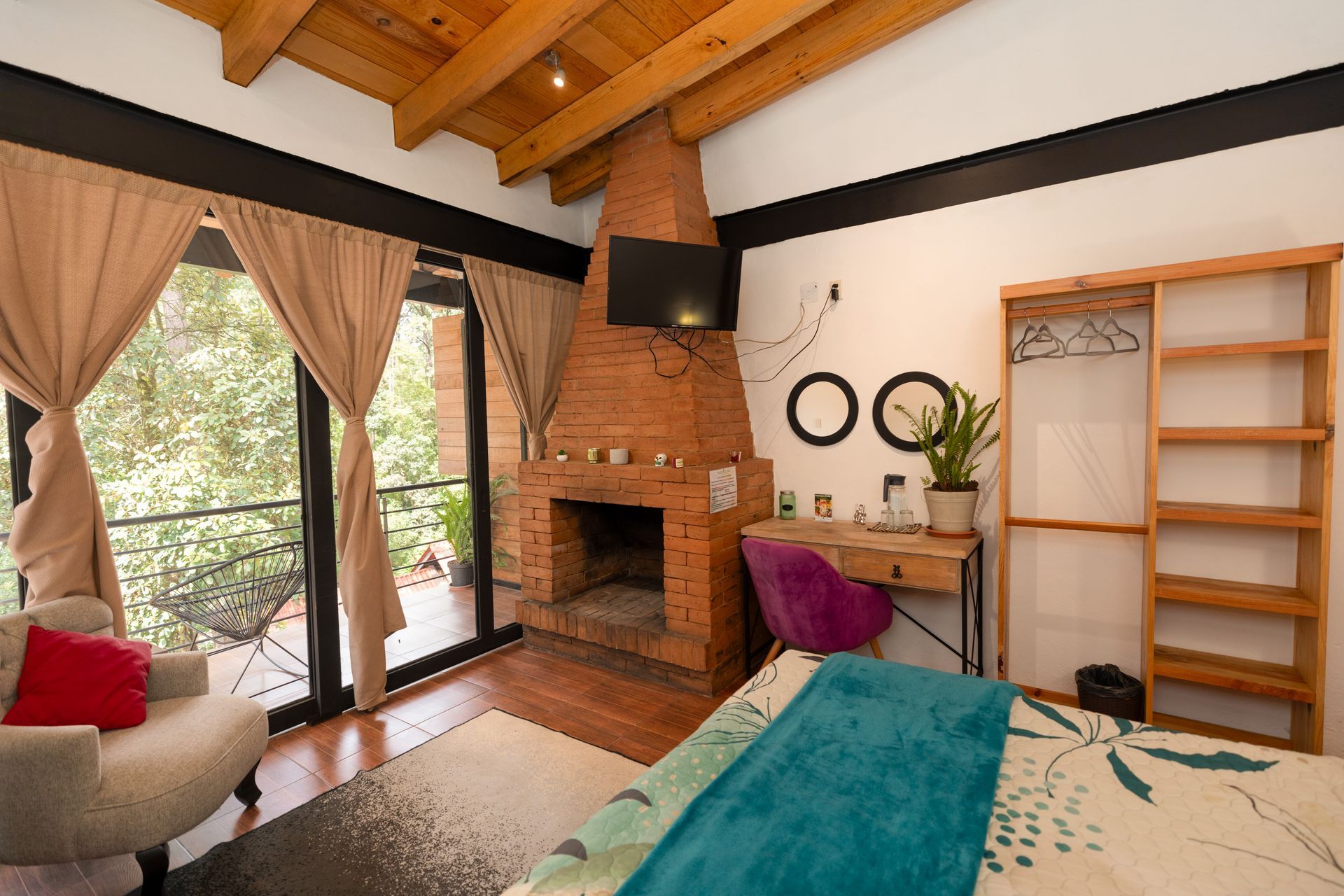 Acogedora habitación tipo cabaña con vigas de madera, chimenea, cama, cortinas y ventana con vistas al lago.
