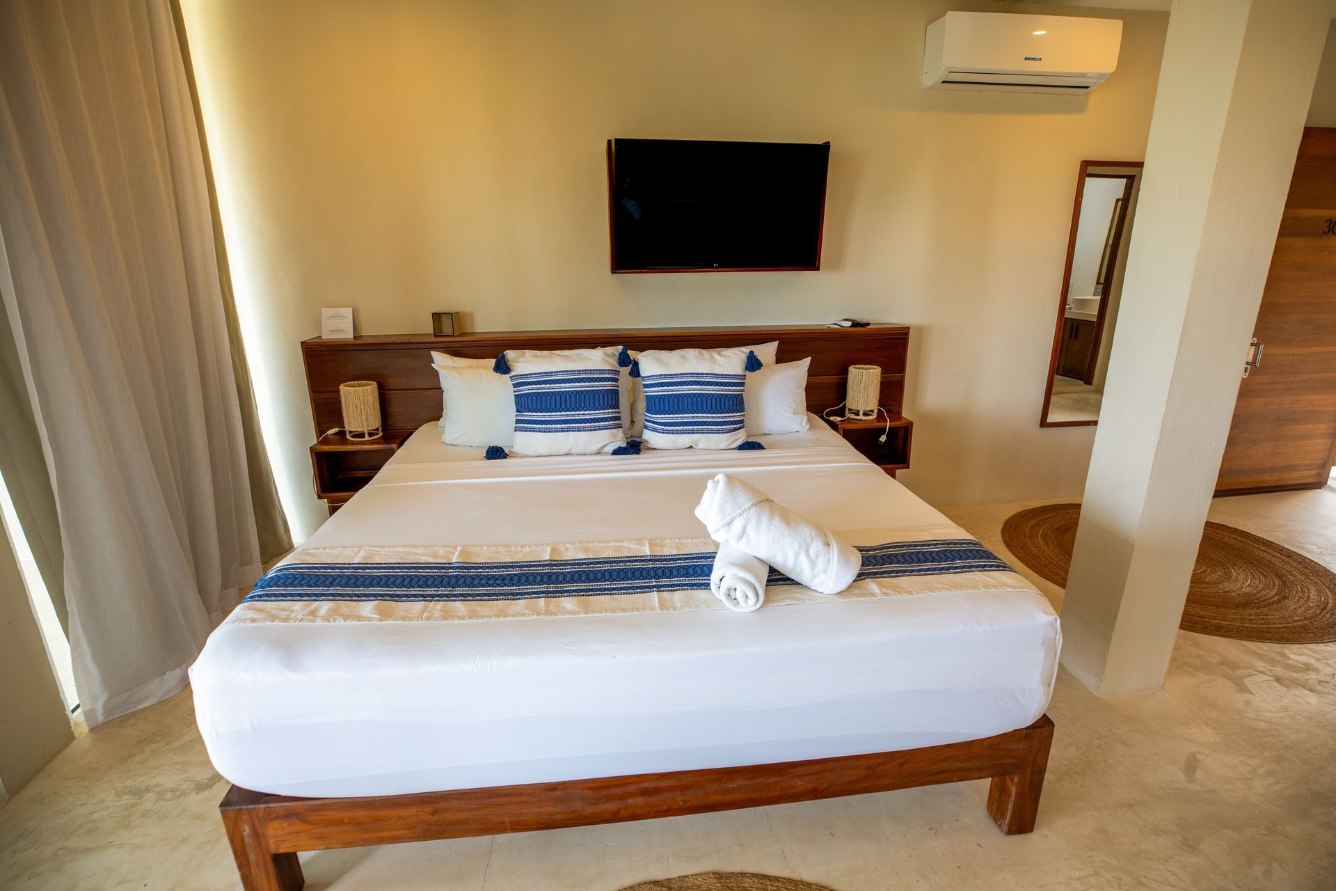Habitación de hotel impecable con cama king size, TV, aire acondicionado, cortinas y suelo de baldosas.