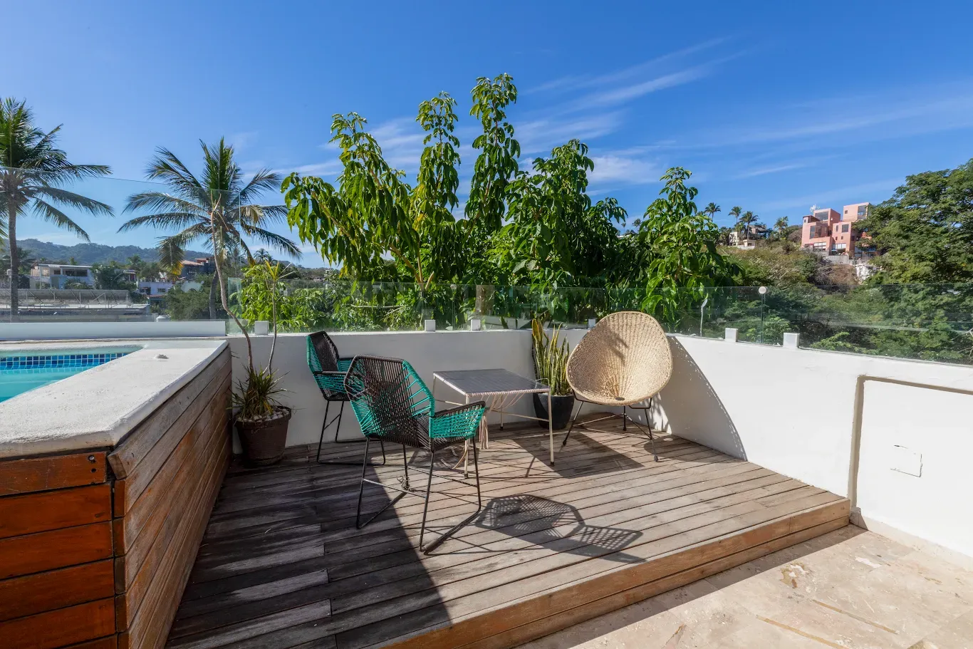Terraza soleada en la azotea con tumbonas, plantas en macetas y vista al mar.