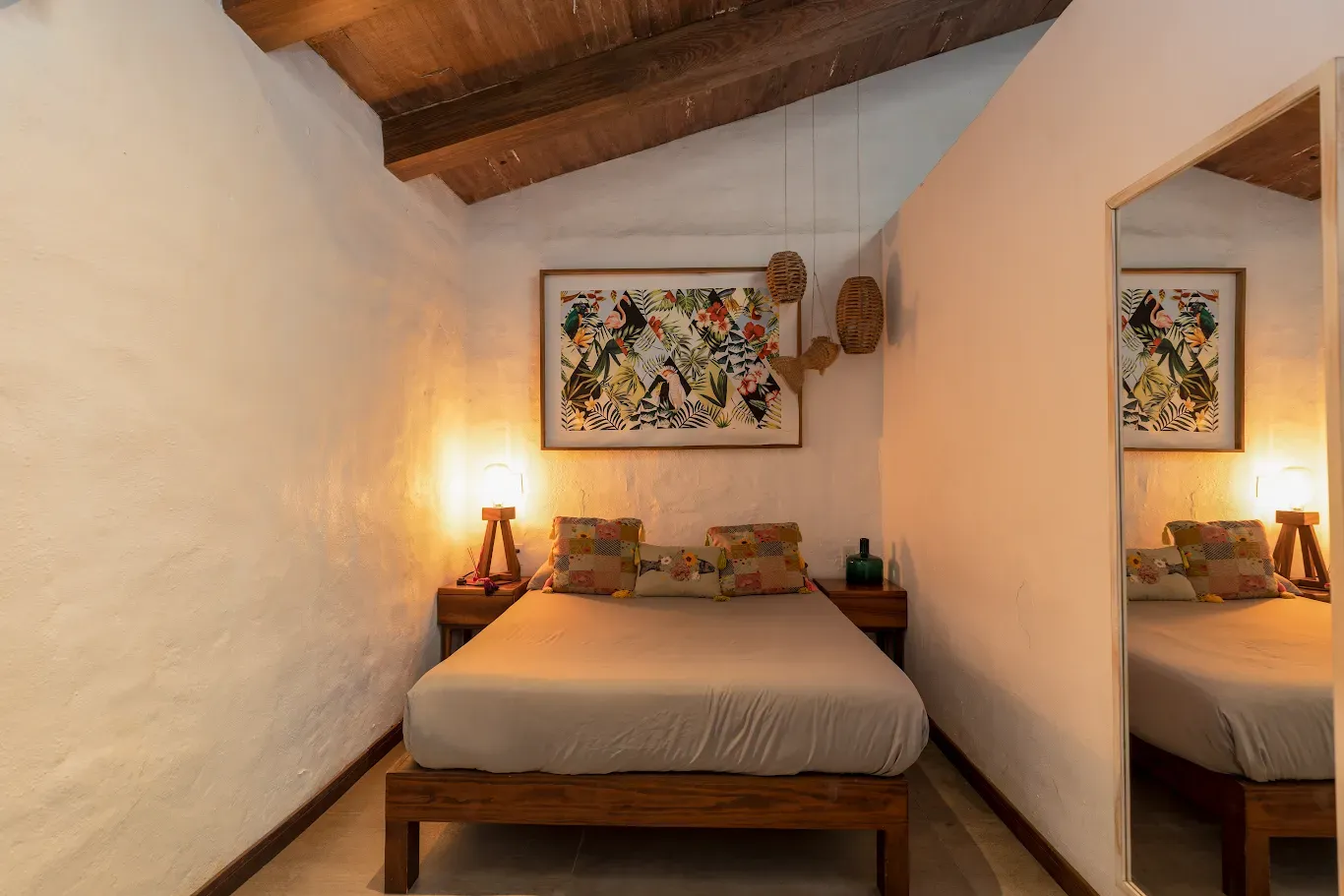 Acogedora habitación con cama de madera, luz cálida de lámpara y decoración floral en la pared, en un loft rústico.