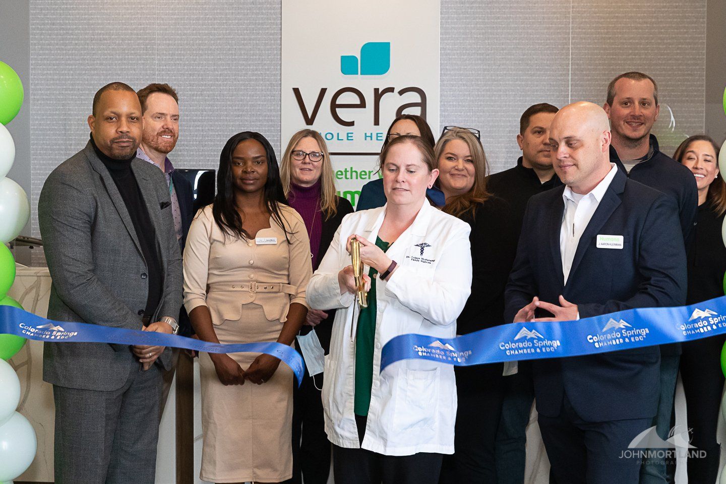 People cutting a blue ribbon in front of a “vera” sign; event.