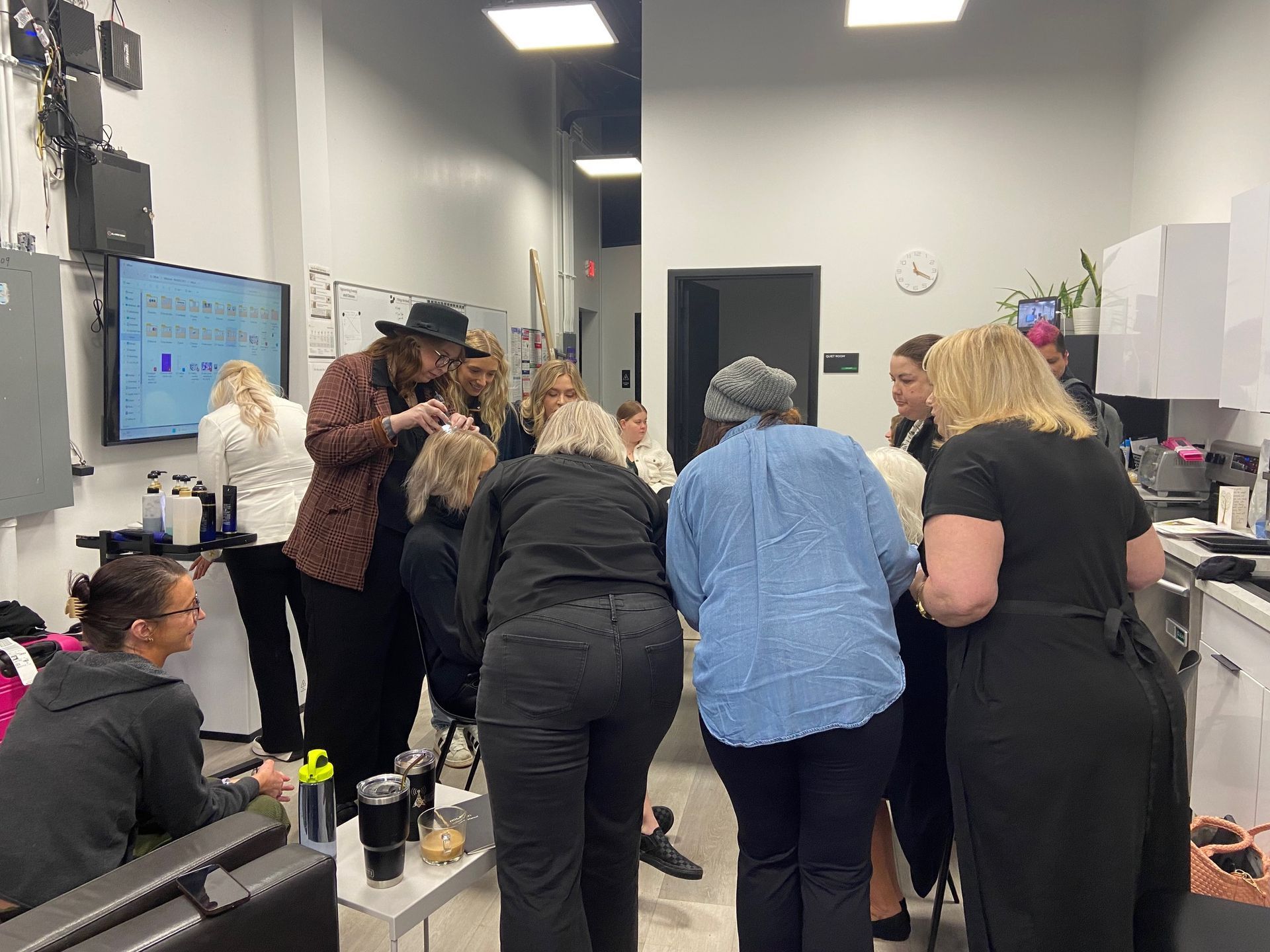 People gathered around, observing a beauty class demonstration.