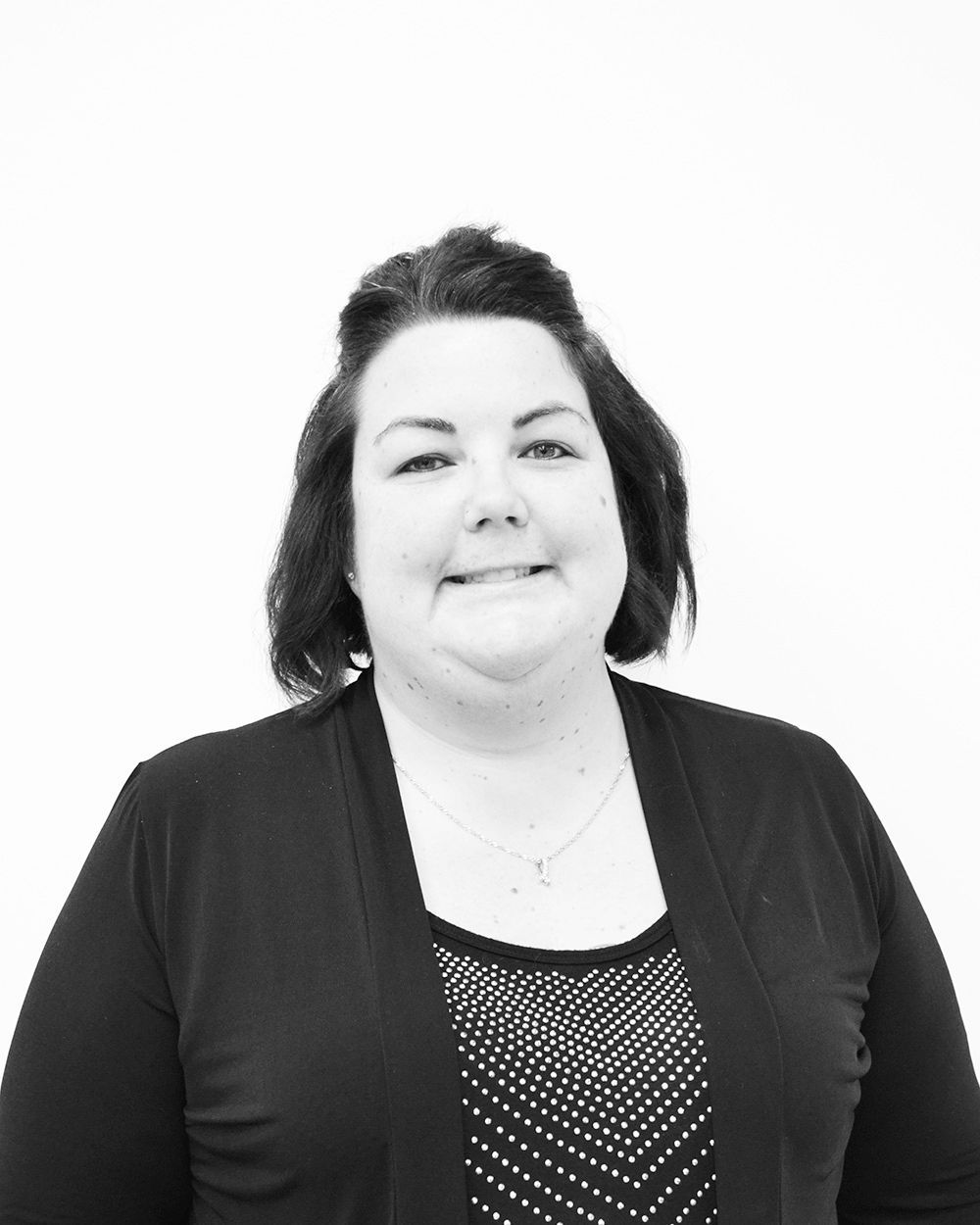 Woman in black cardigan smiling, against a white background.