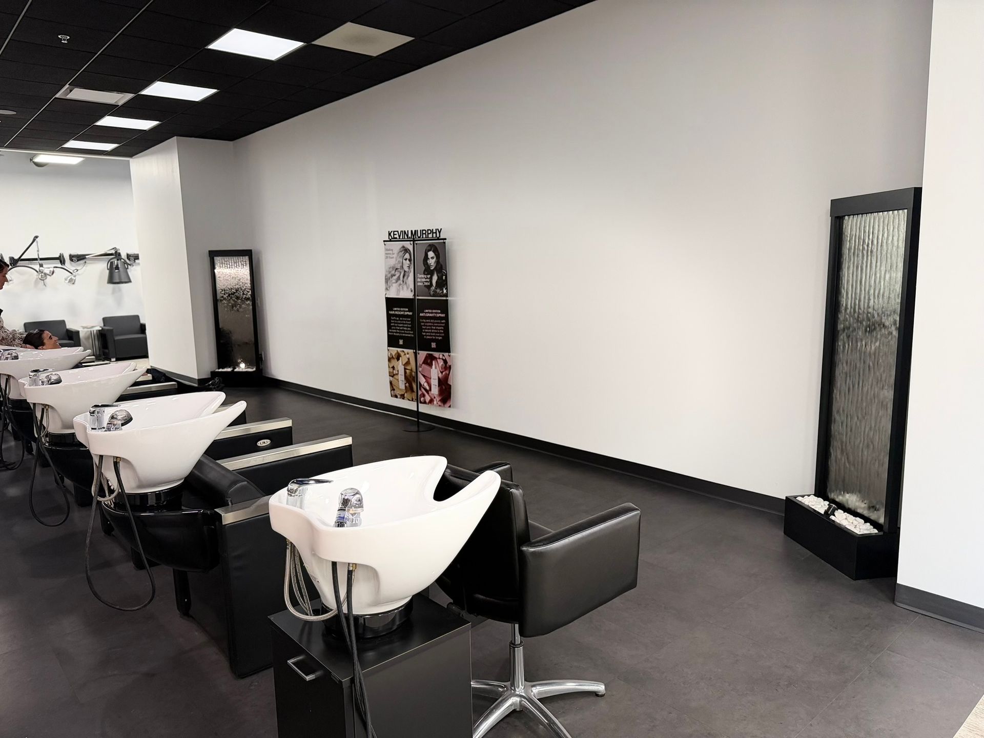 Hair salon interior with wash stations, mirrors, and a decorative water feature.