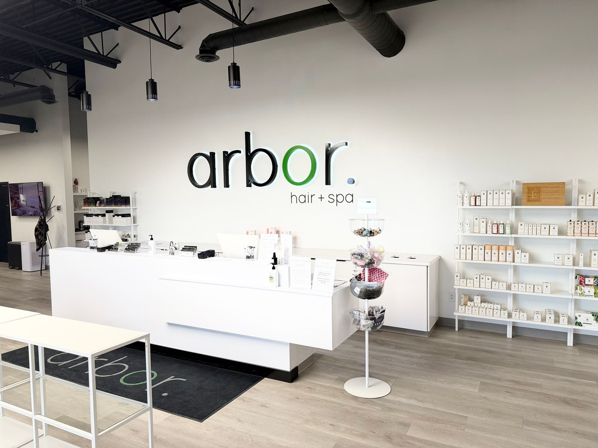 Interior of a hair spa with a white reception desk, product shelves, and the business name 