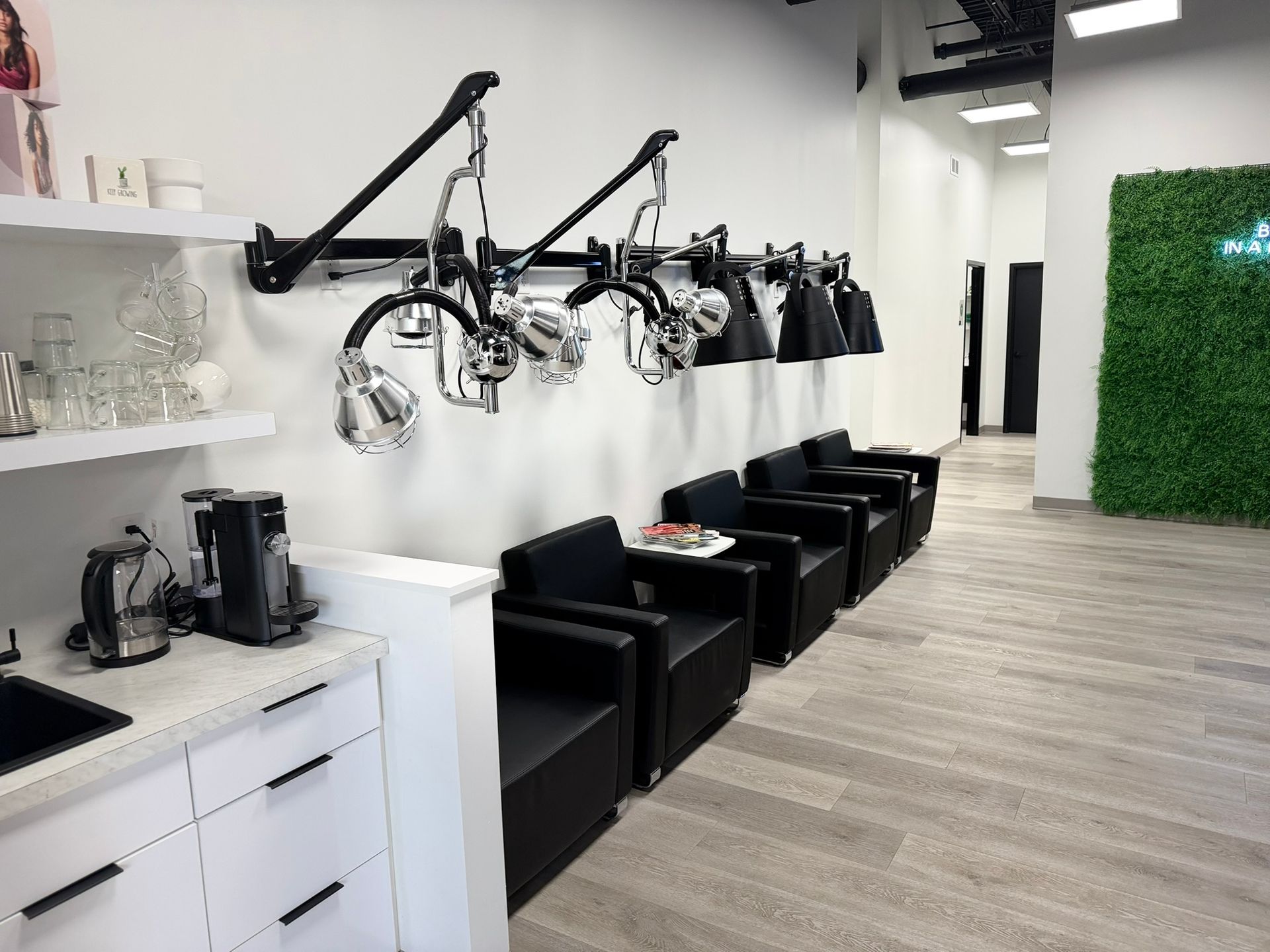 Hair salon interior with styling chairs, hooded dryers, and a coffee station.