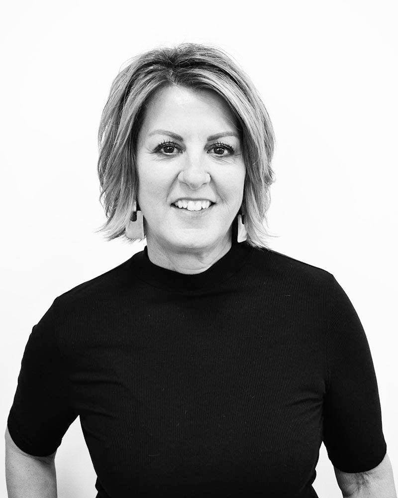 Woman in black turtleneck smiles at the camera, short blonde hair.