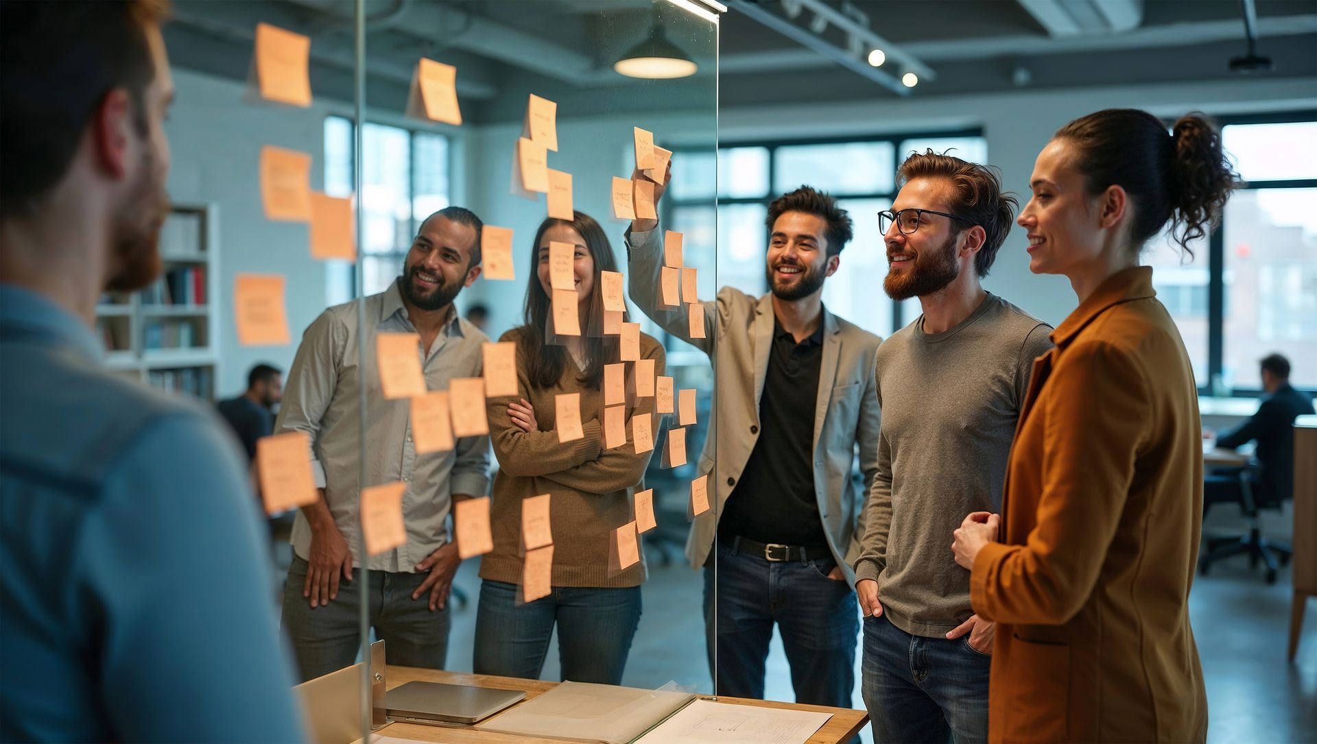 Team in a glass-walled meeting room brainstorming with sticky notes on the window