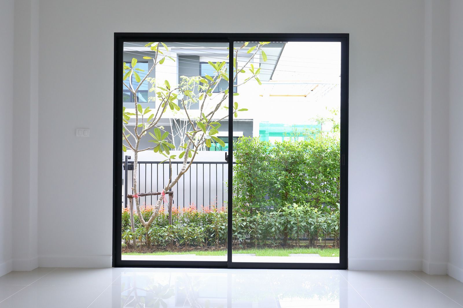 An empty room with a sliding glass door leading to a garden.