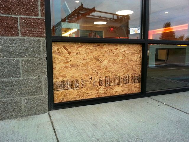 A window with a piece of plywood covering it