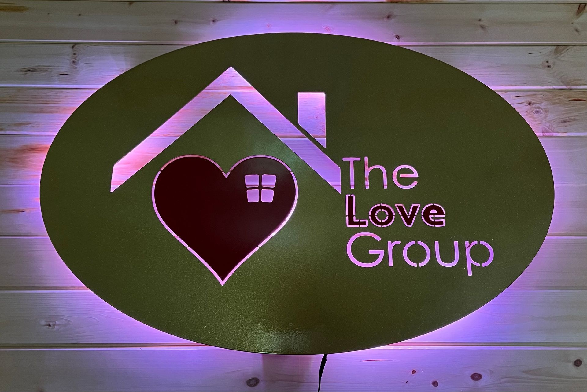An oval sign on a wood wall reads