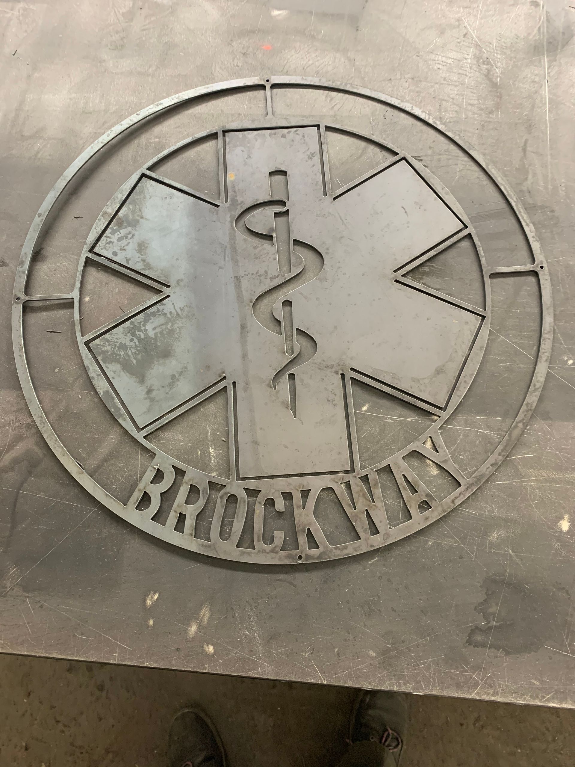 A laser-cut steel emblem of the Star of Life with the word