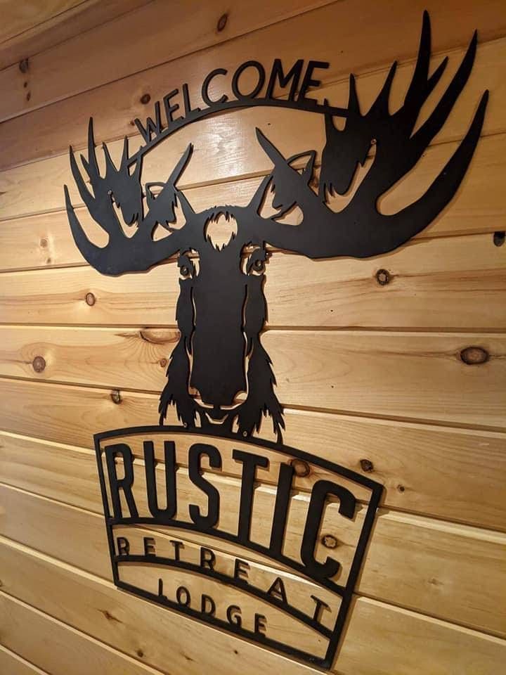 A black metal moose wall sign reads