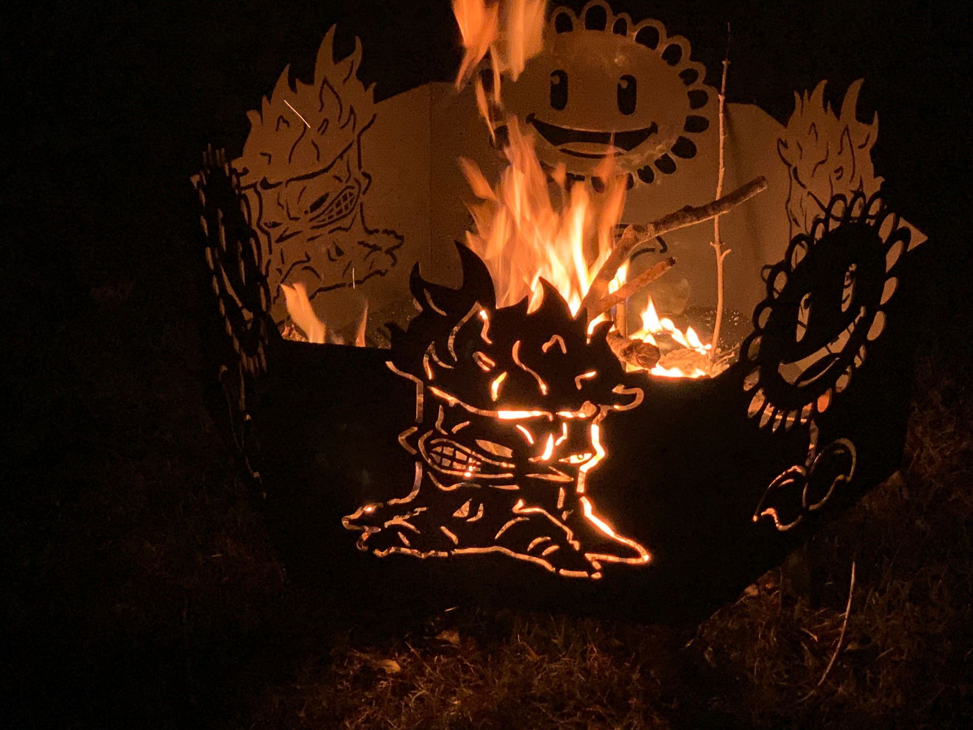 A fire pit glowing with flames, featuring cutouts of smiling and angry plant characters from the game Plants vs. Zombies.