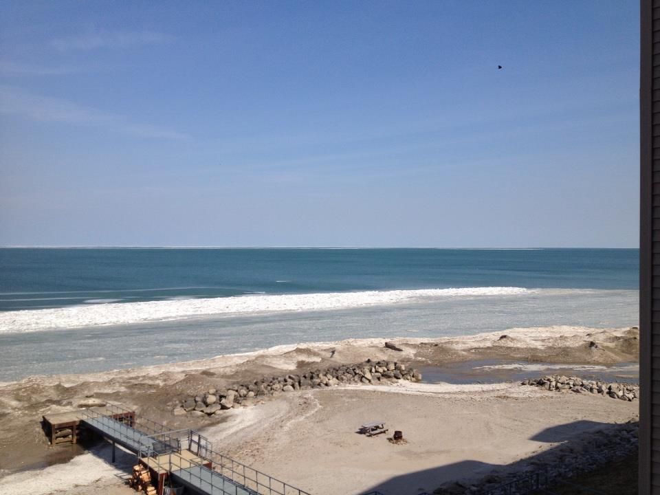 A view of the ocean from a balcony with people on the beach