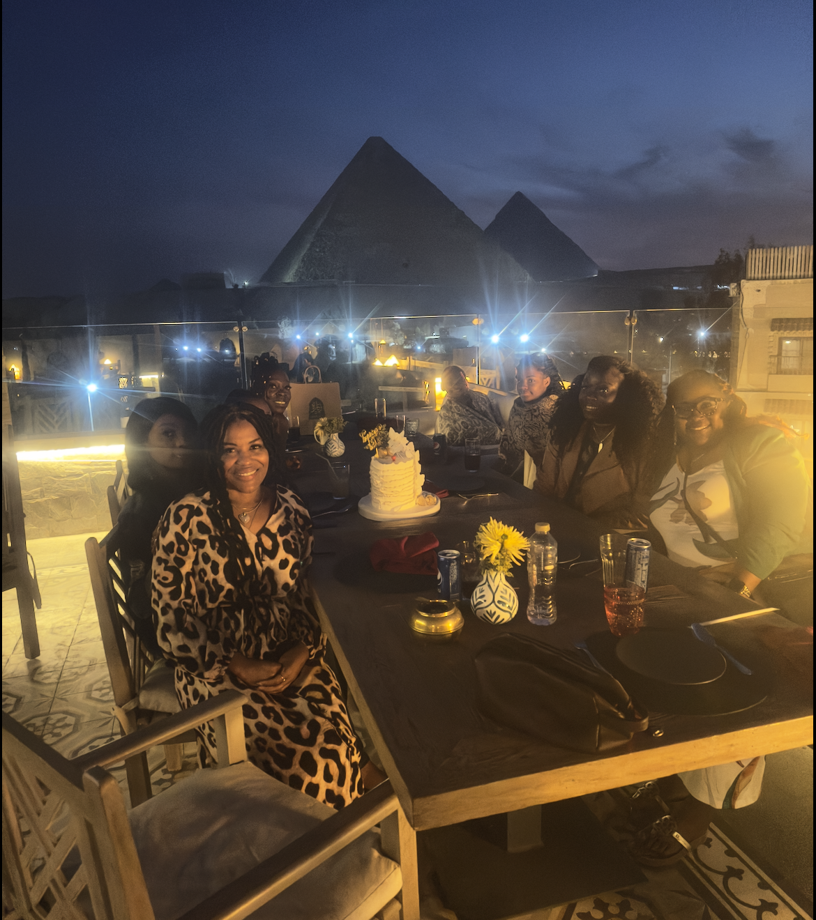 A group of people are sitting at a table with pyramids in the background.