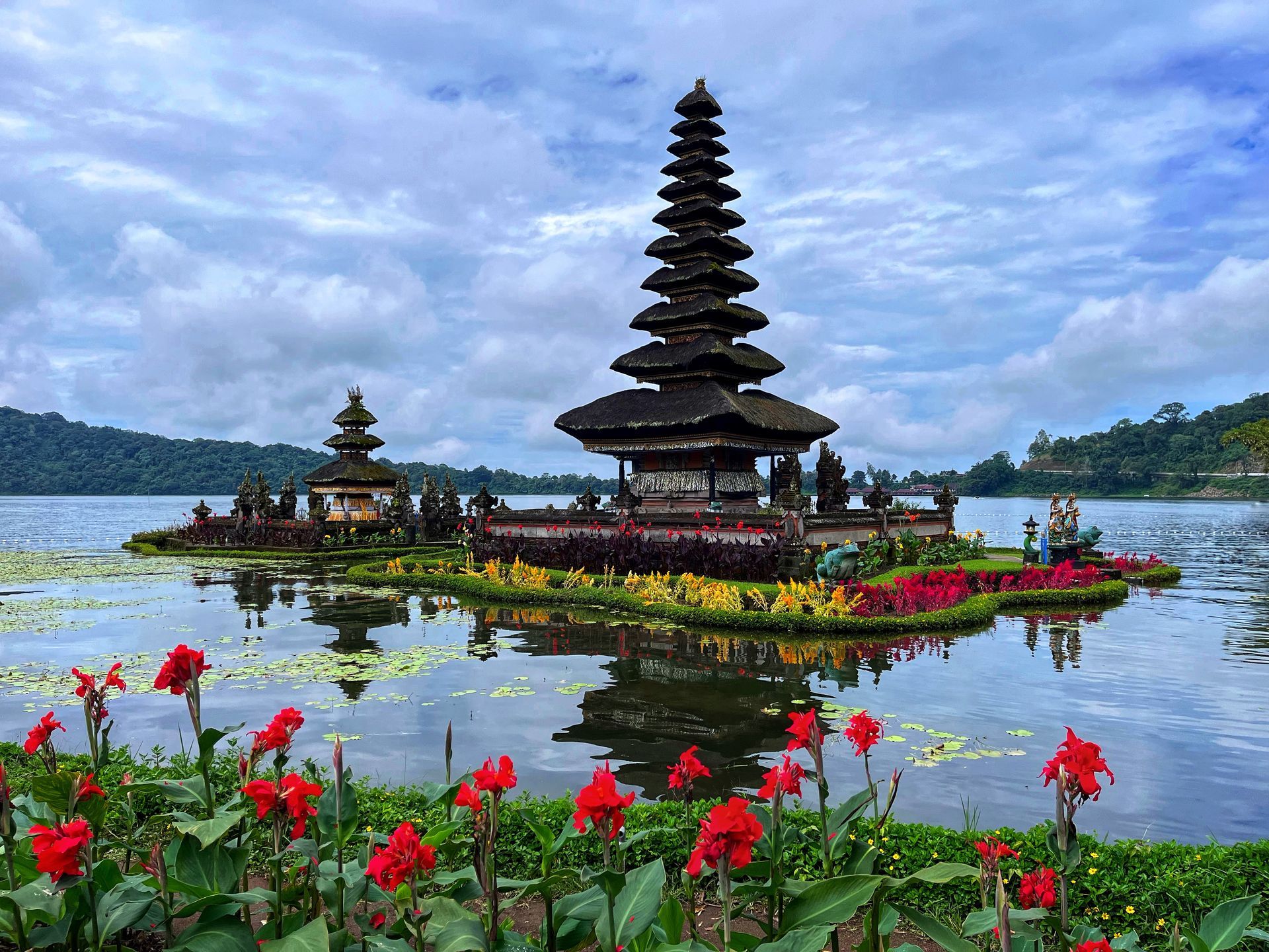 A temple on a small island in the middle of a lake surrounded by flowers.
