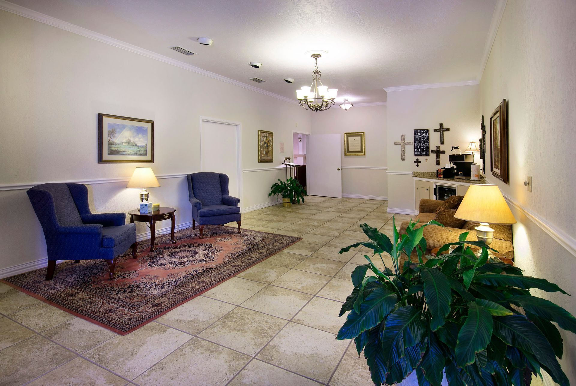 A living room with a couch , chairs , lamps and a plant.