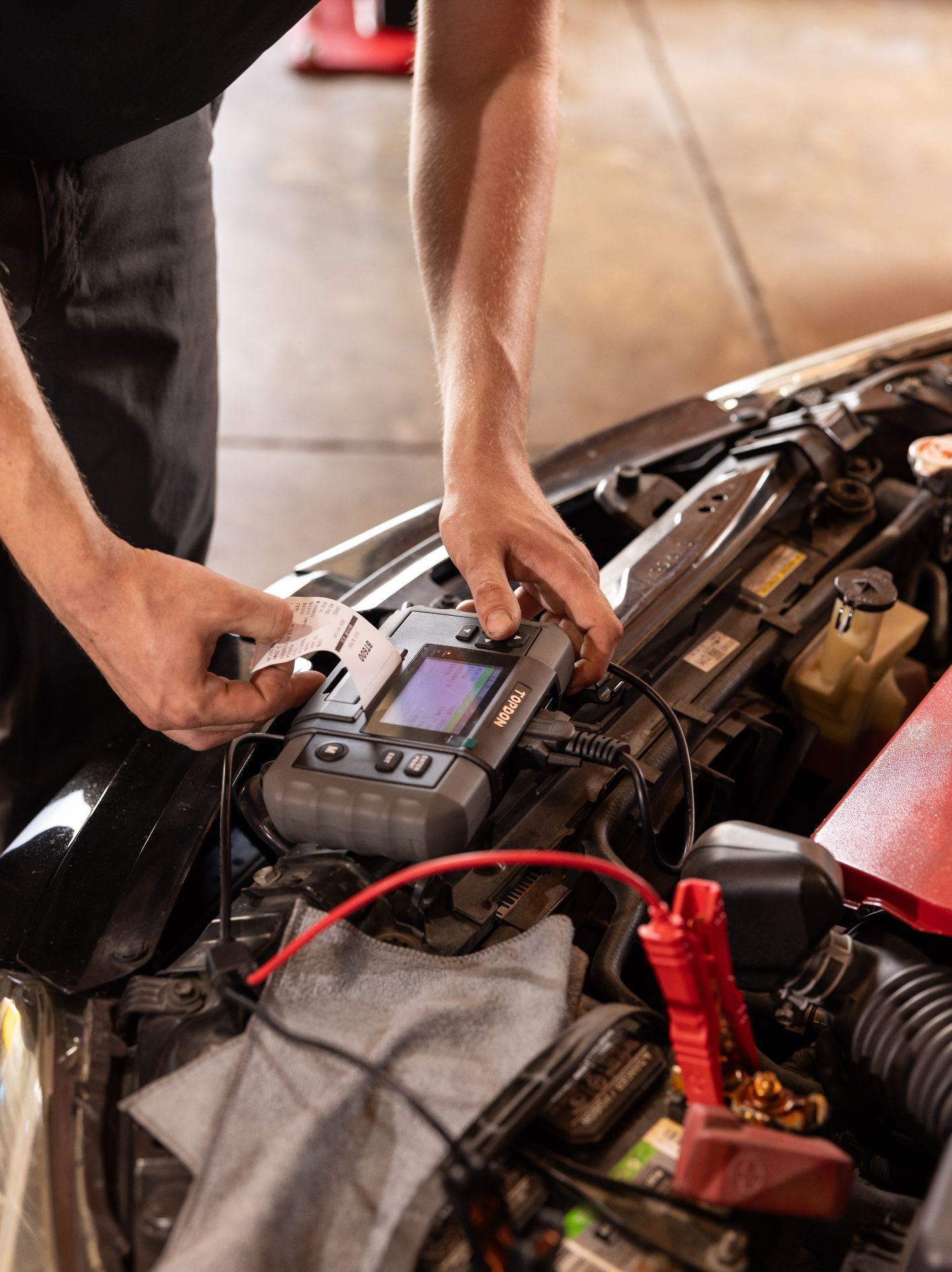 Technician Testing Car Battery Under The Hood | Craig Automotive Services