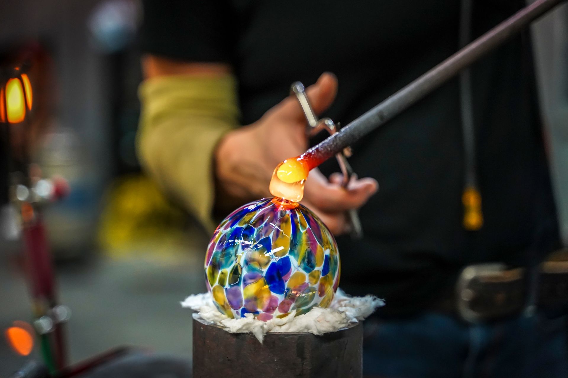 A person is blowing a glass ball with a torch.
