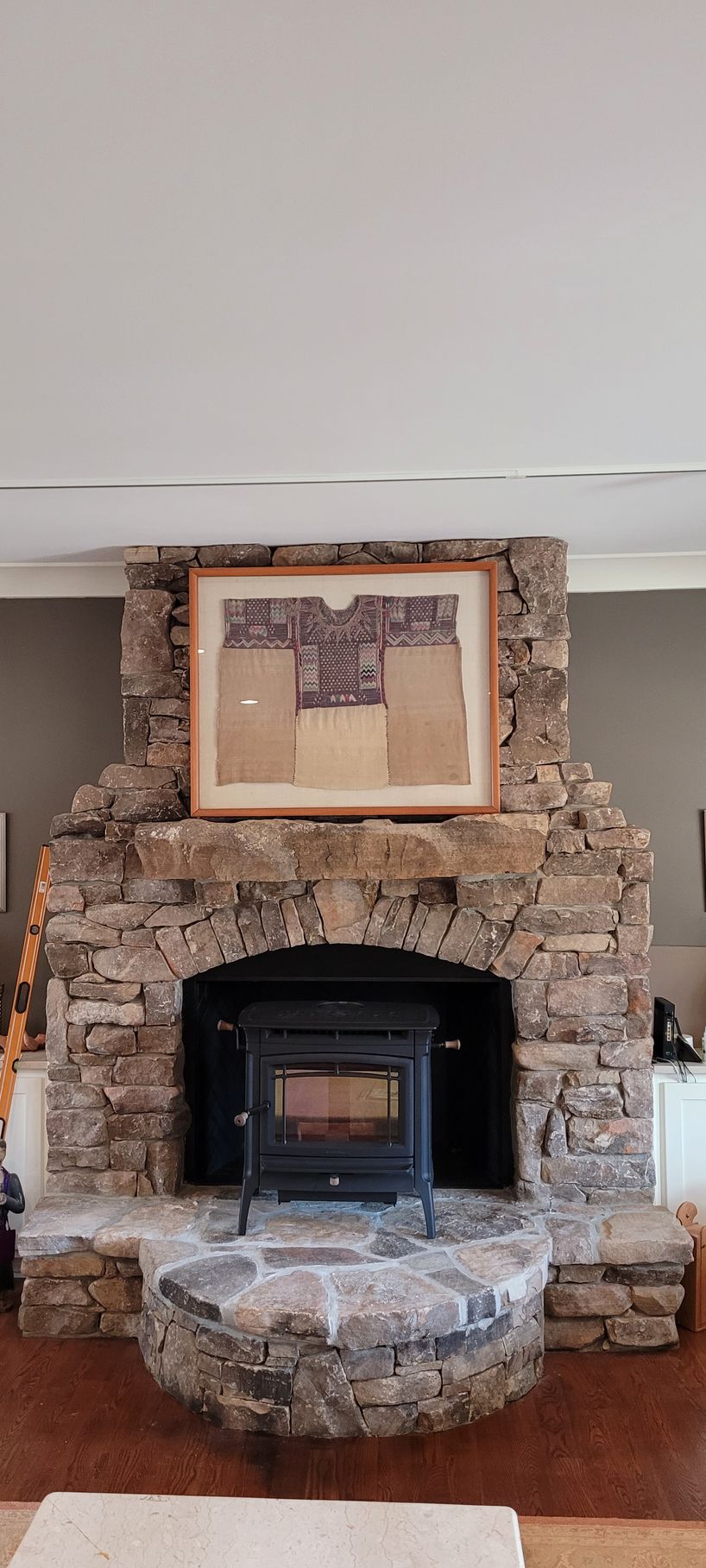 Stone fireplace with a black insert and framed artwork above it in a room