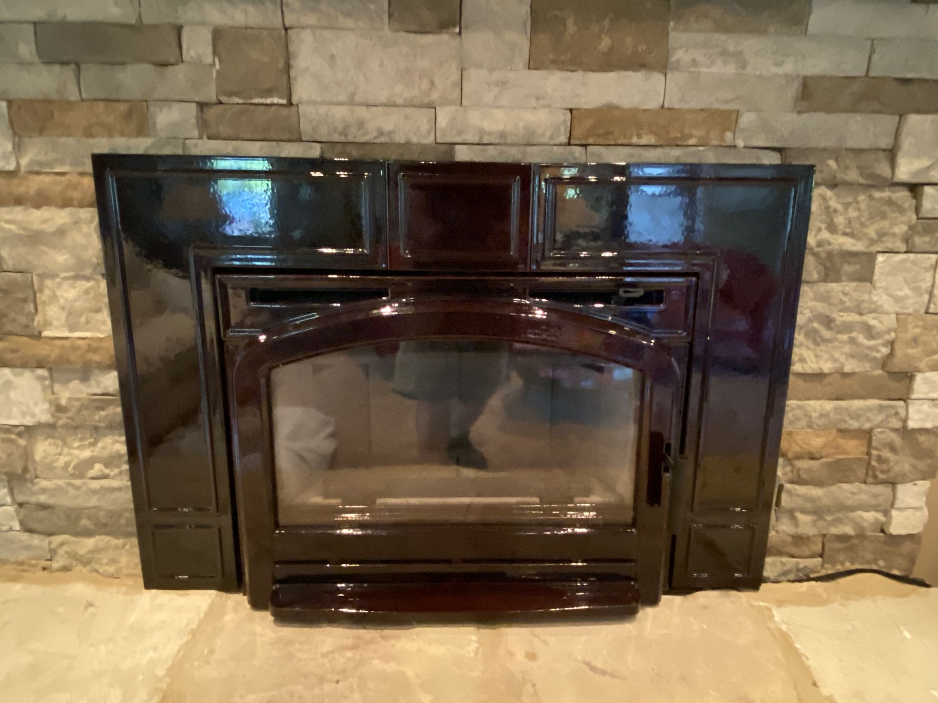 Dark glass fireplace insert set into a stone wall surround