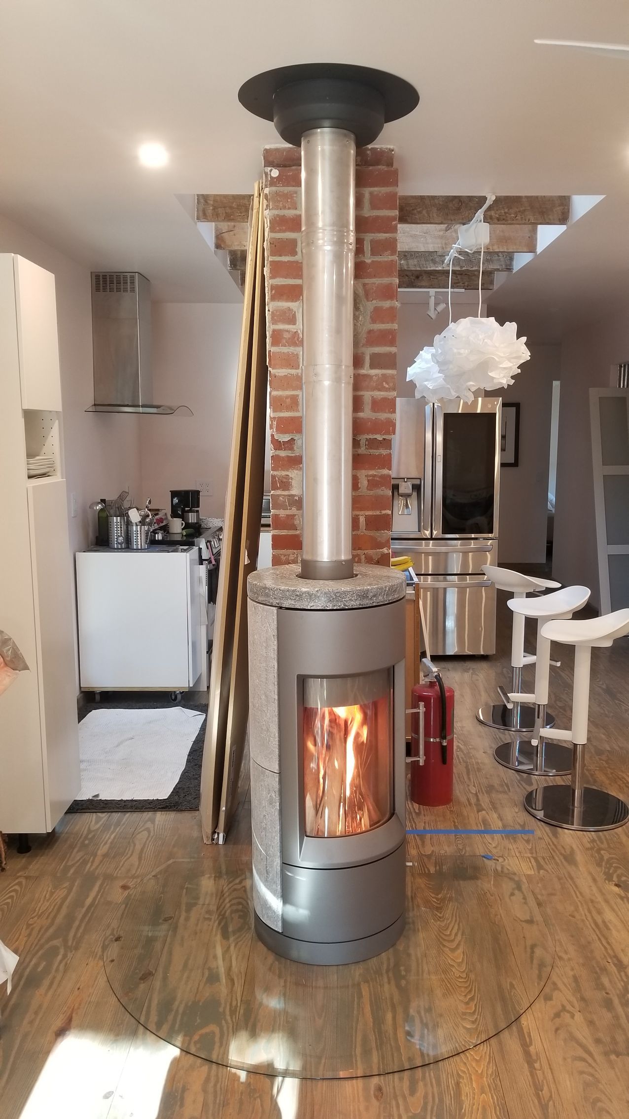 Modern living room with a tall cylindrical fireplace and exposed brick column centerpiece