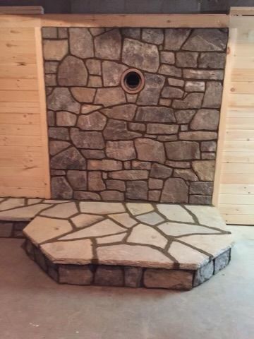 Stone fireplace wall with circular opening and raised stone hearth in an unfinished interior