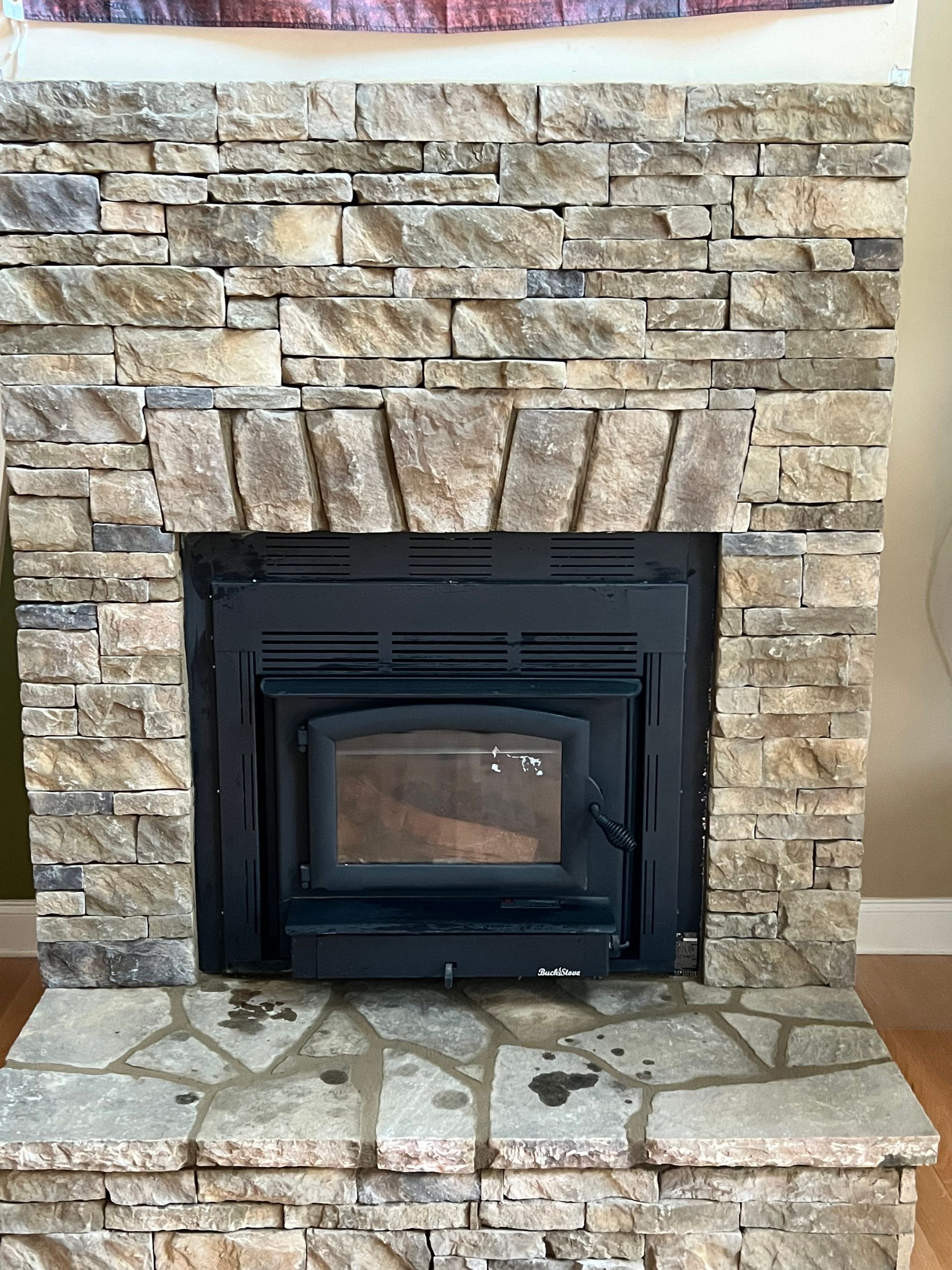 Stone fireplace with a black wood-burning insert and a stone hearth.