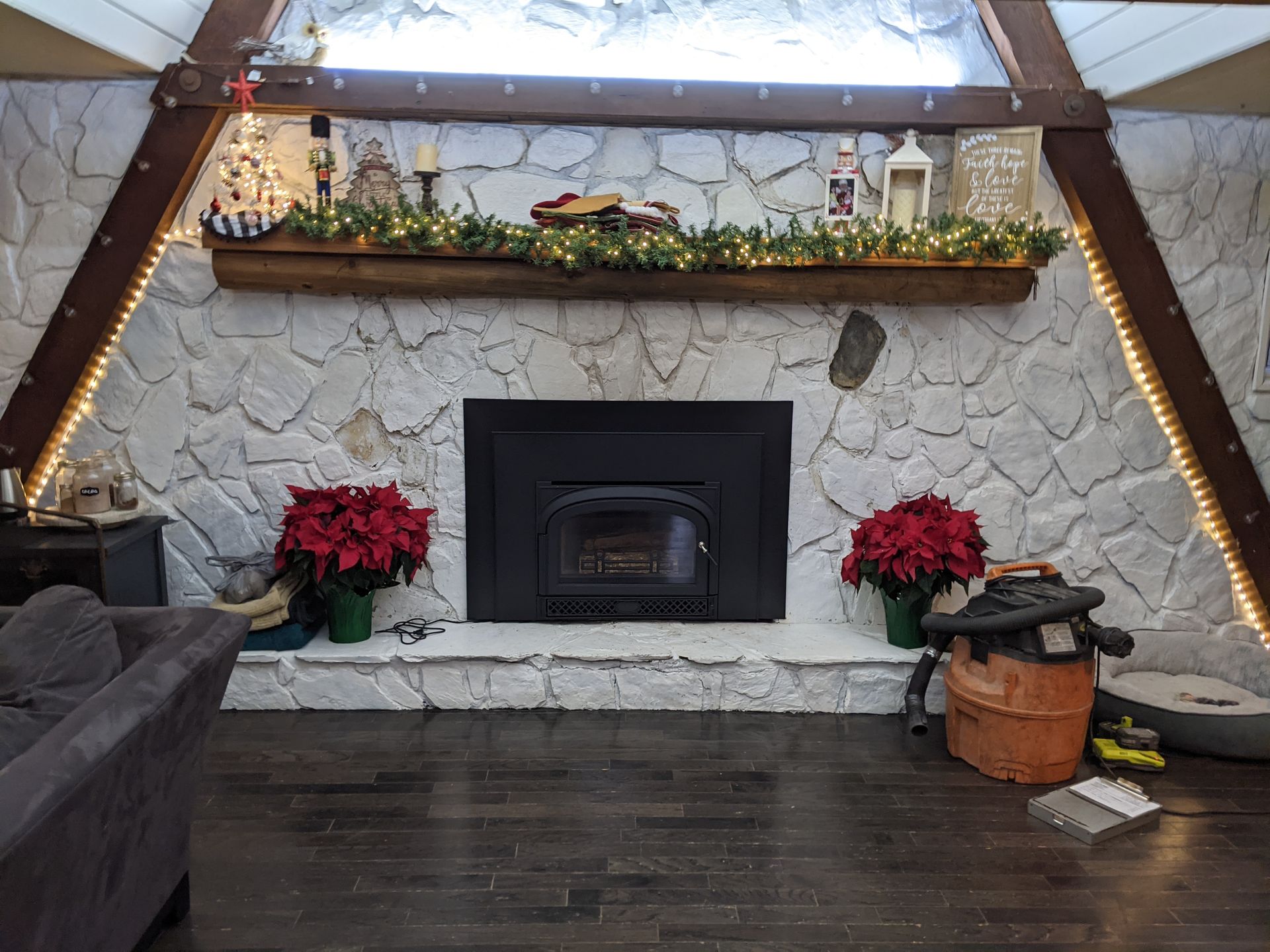 Cozy stone fireplace with wood mantel, red poinsettias, and holiday decor in a cabin-style room