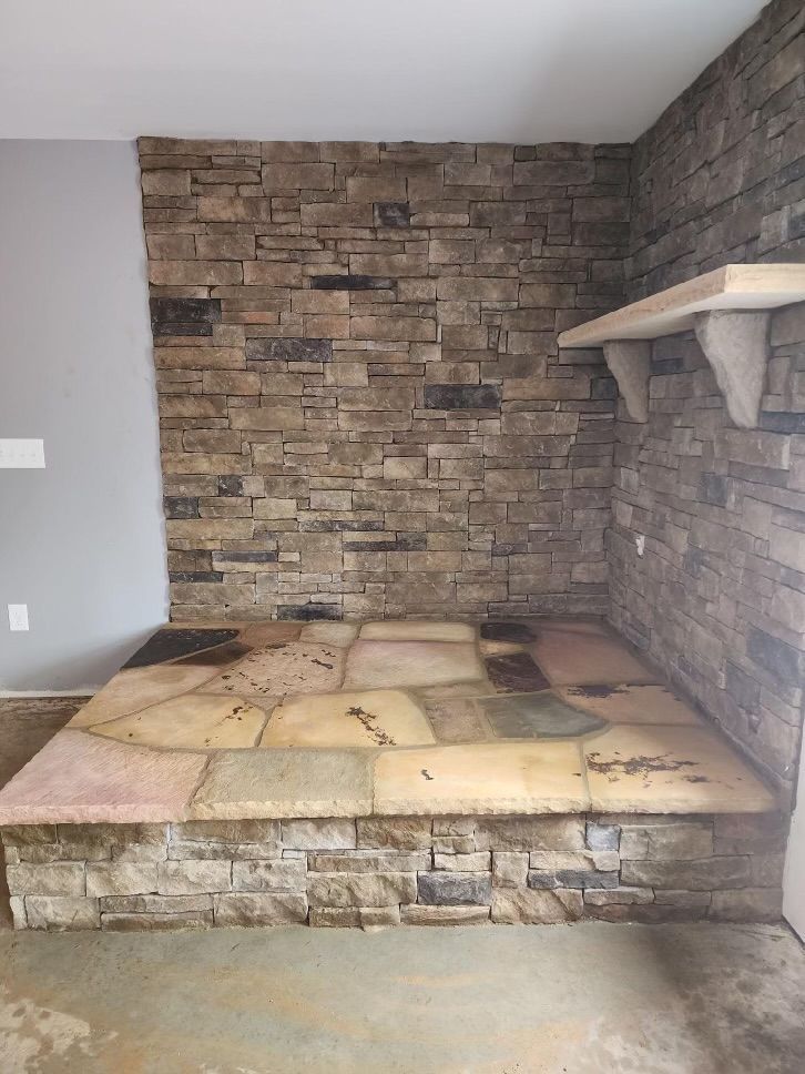 Stone fireplace with a built-in raised hearth and wall shelf in a small room