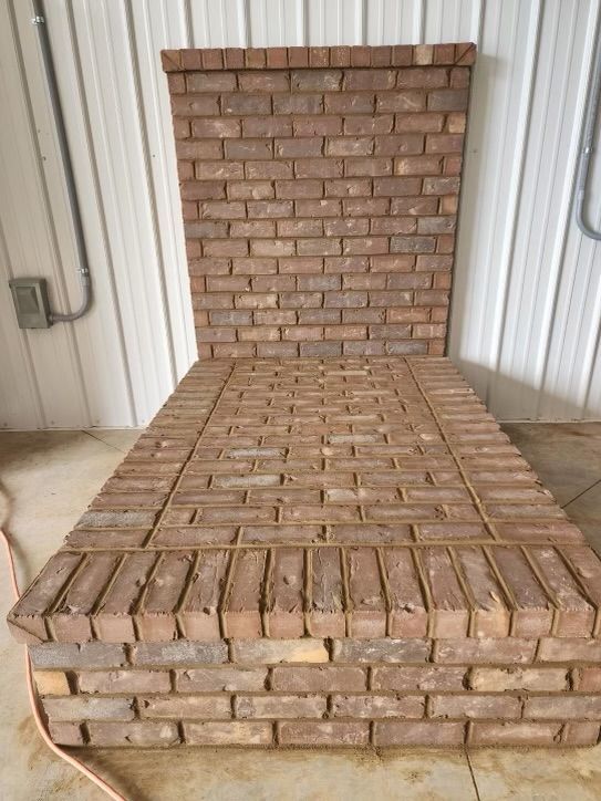 Brick bench with a backrest against a corrugated metal wall in an industrial setting