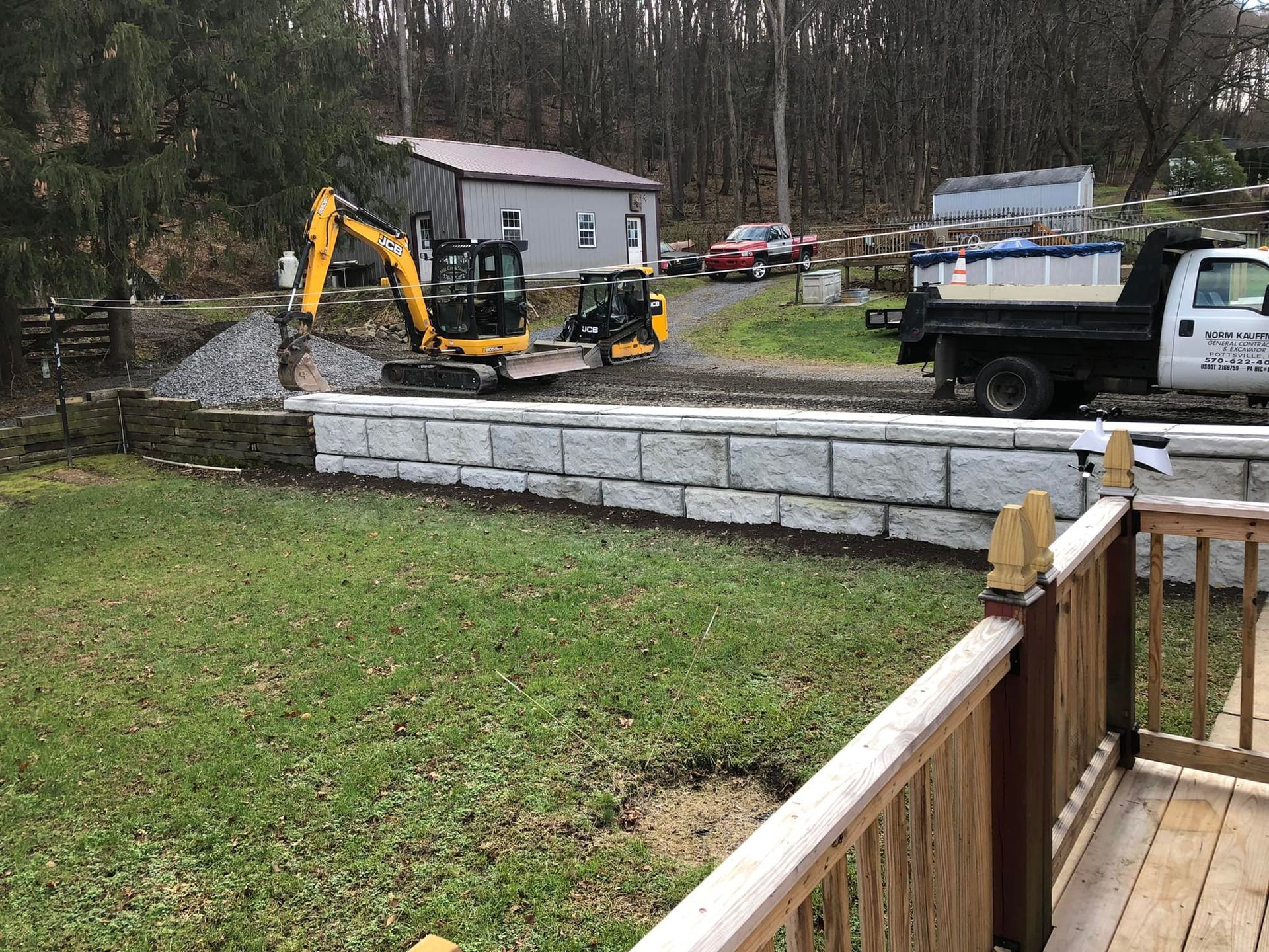 Excavator performing earthmoving near retaining wall installation