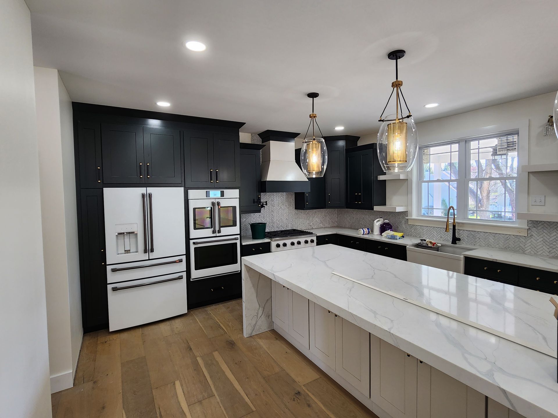 A kitchen with black cabinets , white counter tops , and stainless steel appliances.
