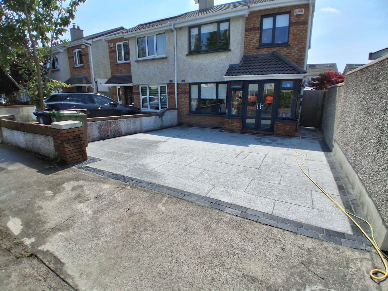 A gravel driveway in front of a brick building with a granite stone border.
