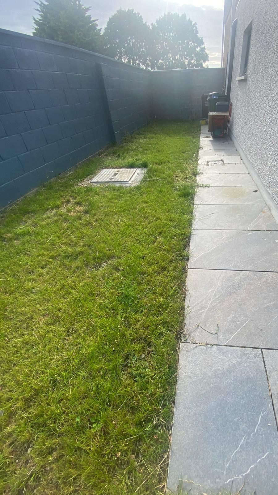 Lawn and stone path alongside a building and a black fence.