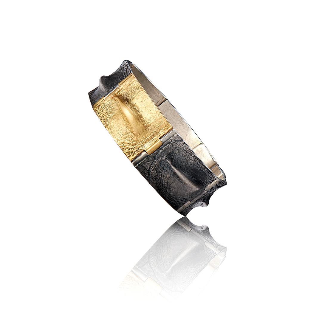 Auf einer weißen Fläche liegt ein schwarz-goldener Ring.