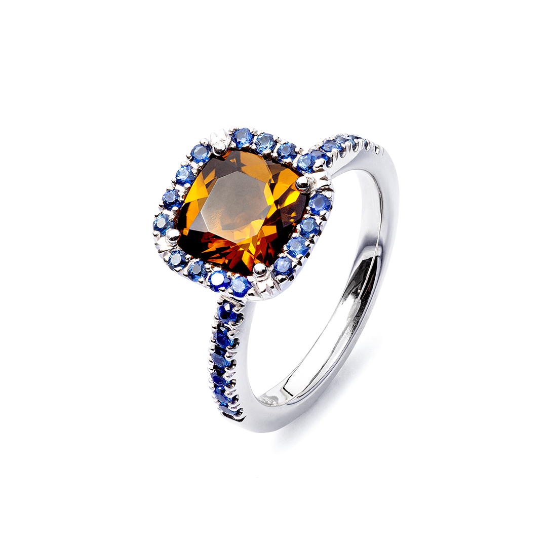 ein Ring mit einem quadratischen Stein und blauen Saphiren auf weißem Hintergrund.