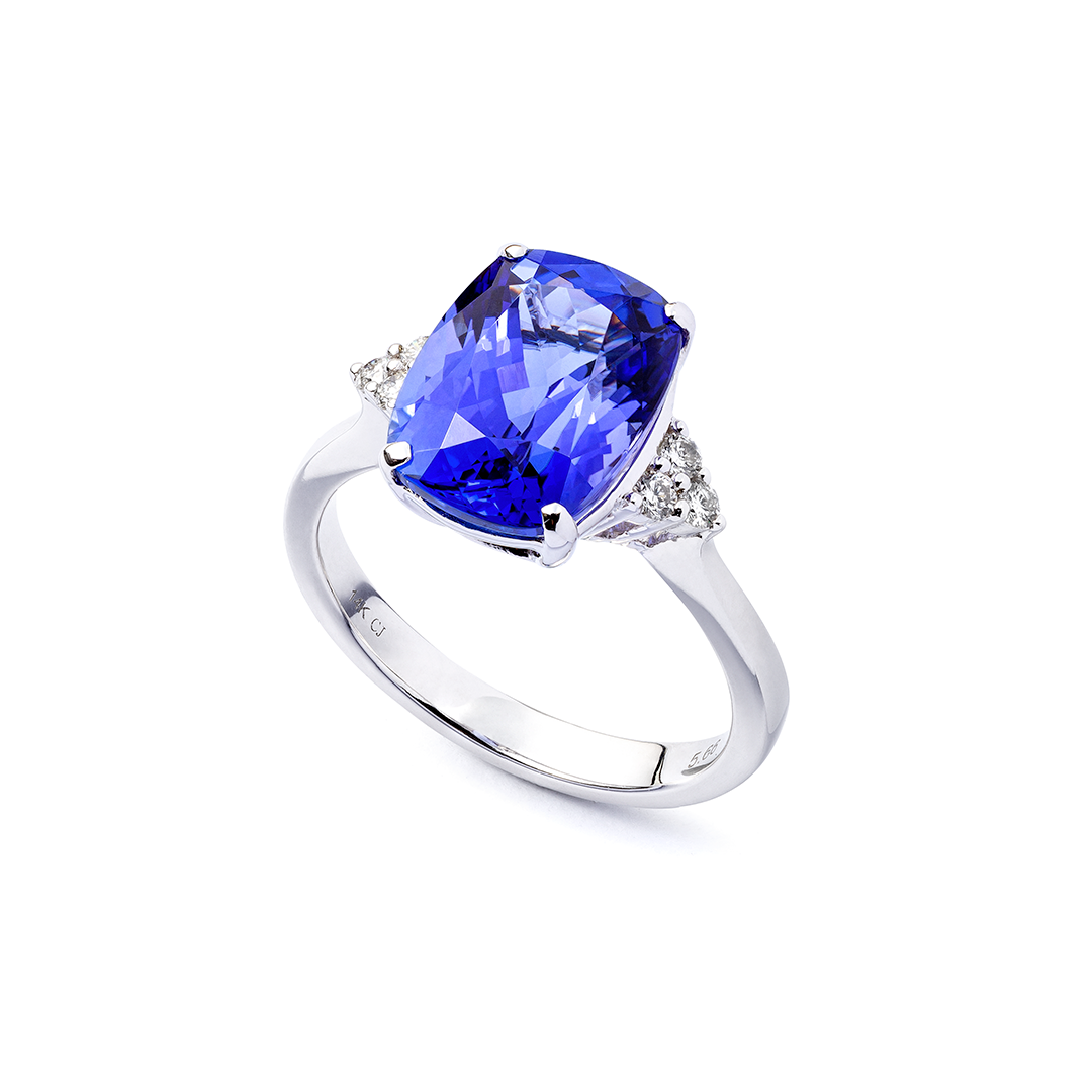 ein Weißgoldring mit einem Saphir und Diamanten auf weißem Hintergrund.