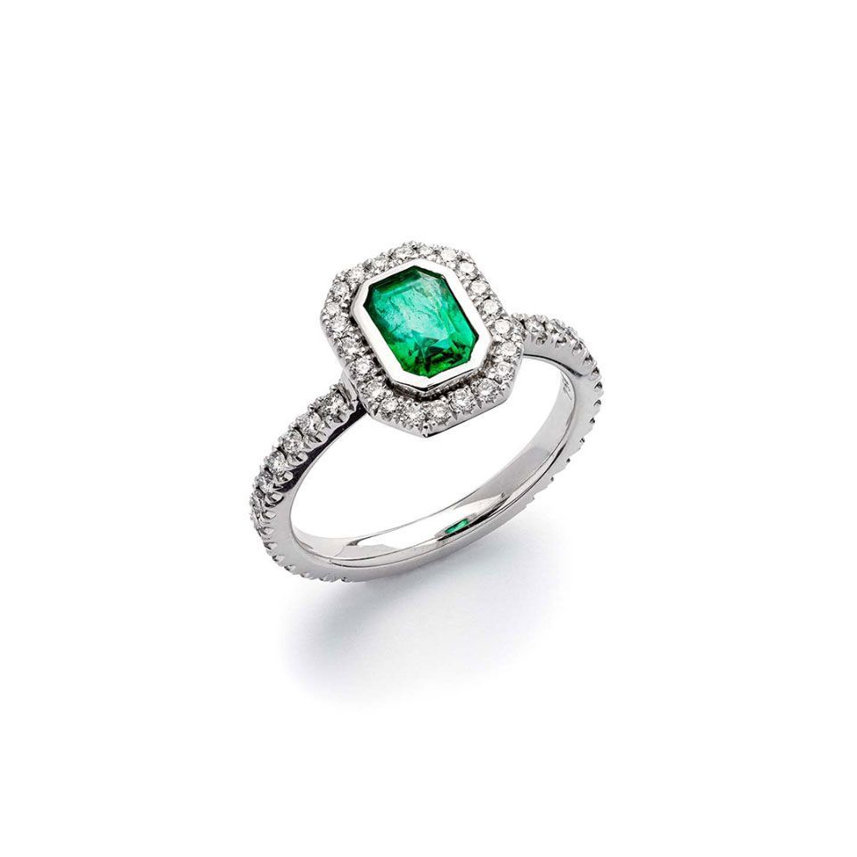 ein Ring mit einem Smaragd und Diamanten auf weißem Hintergrund .