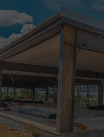 Construction site with steel framework and cloudy sky.