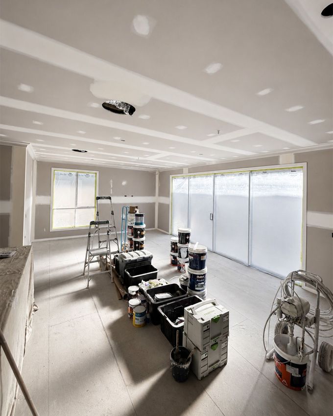Bright, empty modern room with wood floors, white walls, ceiling fan, and tall windows.