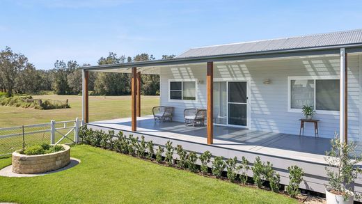 White modern house with terracotta roof on a sunny hill, with green lawn and blue sky