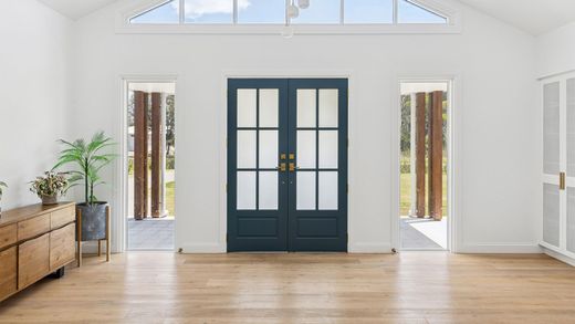Bright minimalist room with wood floors, white walls, a ceiling fan, and hallway windows.
